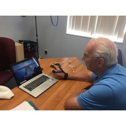 Un homme se concentrant après une attaque cérébrale s'exerce avec MusicGlove sur son ordinateur.