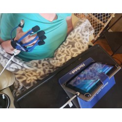 Eine konzentrierte Frau nach einem Schlaganfall trainiert mit einem MusicGlove auf einem Tablet.